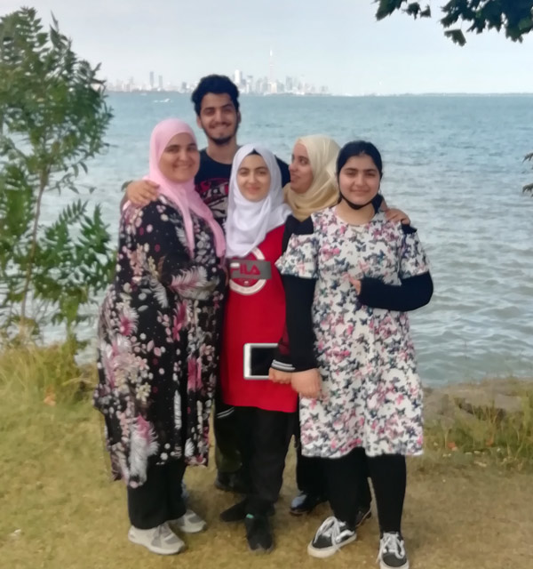 A group photo with Wisam in front of Lake Ontario. The Toronto skyline is in the distance.
